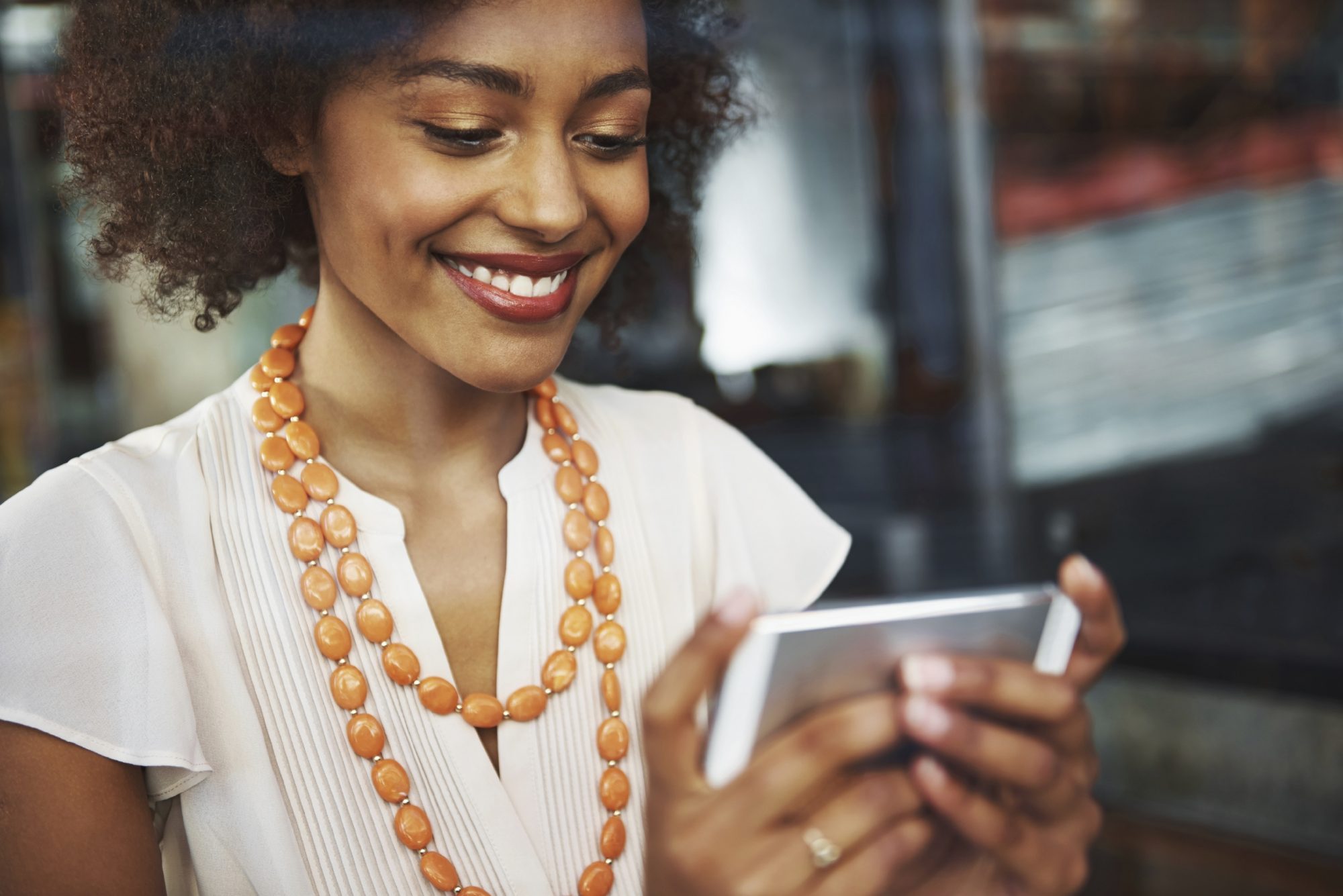 African american young professional woman in a blouse and modern style jewelry on a smartphone