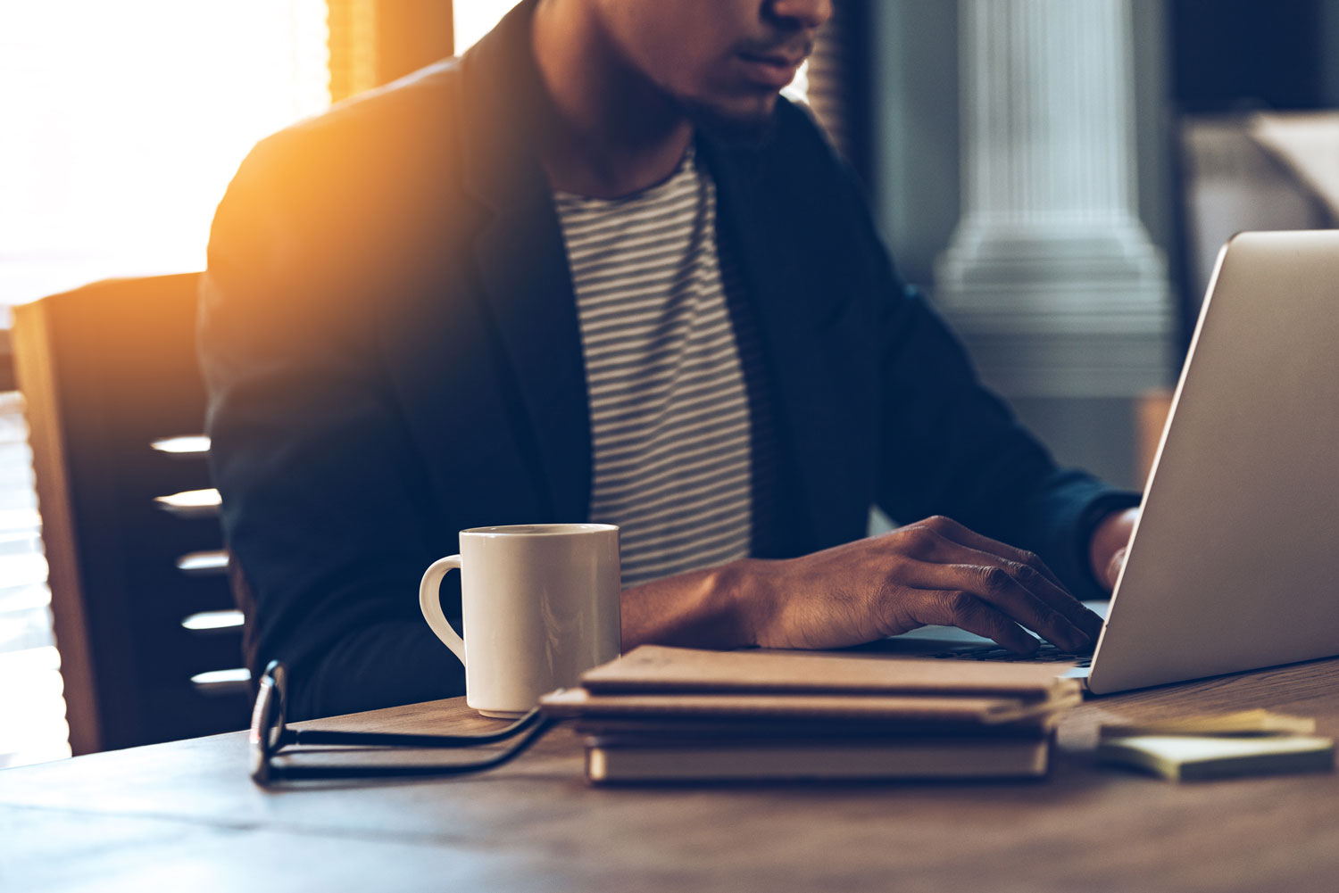 young African american man at a work desk with coffee and laptop