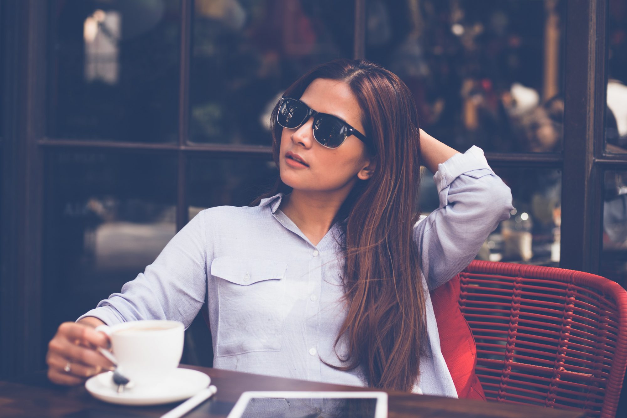 stylish young woman having coffee at an outdoor cafe patio