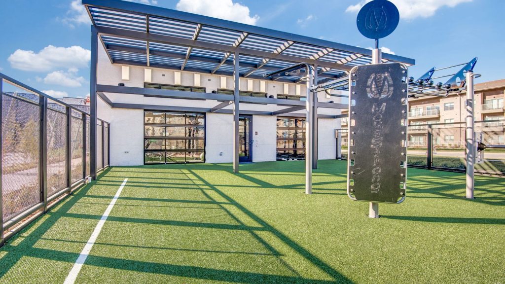 Outdoor Crossfit area with turf ground, a view into the fitness center, and a cabana roof
